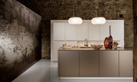 Deze luxe keuken, bestaande uit een hoge keukenwand en een keukeneiland, werkt kalm door de beige en crème-tint. Het ontwerp is symmetrisch en de meubels zijn onverstoord door grepen of versieringen. Zuordnung: Stil Luxe keukens, Planungsart Detail keukenontwerp