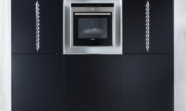 Luxe hoogkast met apparatuurkast. Matzwart met verticaal ornament. In het midden een vak voor inbouwapparatuur zoals de oven. Zuordnung: Stil Luxe keukens, Planungsart Open keuken (woonkeuken)